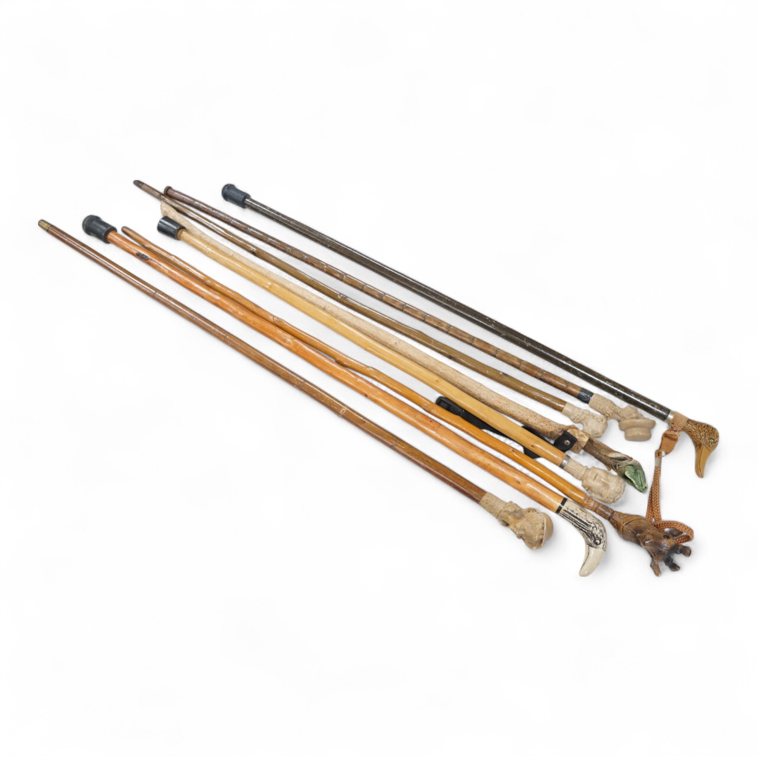 A collection of eight mostly moulded resin mounted walking canes to include one in the form of a lizard, largest 93cm in length